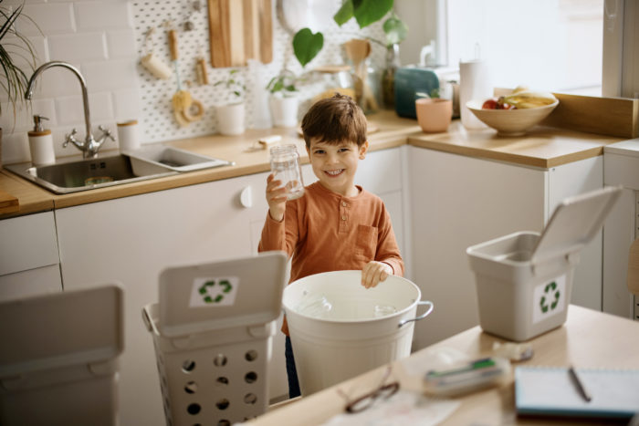 Portrait of a cute little boy holding glass waste for recycling